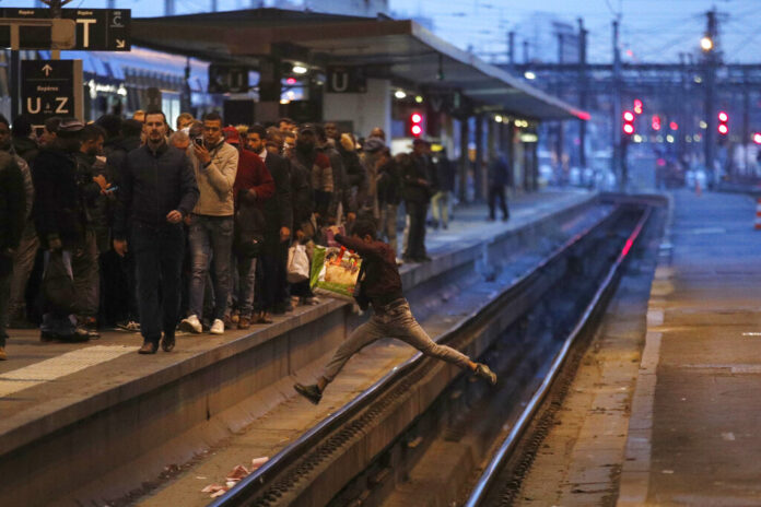 In this Tuesday, April 3, 2018 file photo a passenger crosses railroad tracks at rush hour at Gare de Lyon train station, in Paris. France's rail operator SNCF and the Paris Metro say nationwide strikes will wipe out most services Thursday, impacting millions. The SNCF expects that 9 out of 10 high-speed trains won't run and that half of the Eurostar services linking France and Britain will be canceled, too. Photo: Francois Mori, File / AP