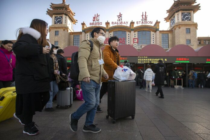 A traveler wears a face mask as he walks outside of the Beijing Railway Station in Beijing, Monday, Jan. 20, 2020. (AP Photo/Mark Schiefelbein)