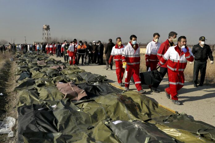 Rescue workers carry the body of a victim of a Ukrainian plane crash in Shahedshahr, southwest of the capital Tehran, Iran, Wednesday, Jan. 8, 2020. (AP Photo/Ebrahim Noroozi)