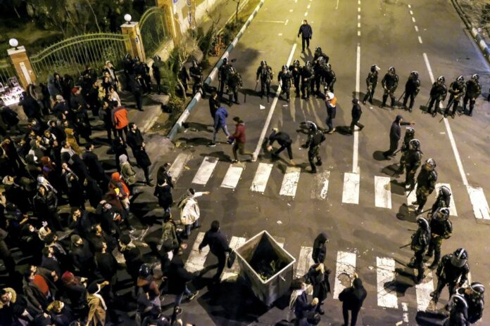 In this photograph taken Saturday, Jan. 11, 2020, Iranian police officers take position while protesters gather in front of Amir Kabir University in Tehran, Iran, to remember victims of a Ukrainian airplane shot down by an Iranian missile. (AP Photo)