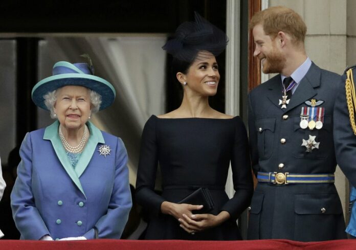 In this Tuesday, July 10, 2018 file photo Britain's Queen Elizabeth II, and Meghan the Duchess of Sussex and Prince Harry watch a flypast of Royal Air Force aircraft pass over Buckingham Palace in London. (AP Photo/Matt Dunham, File)