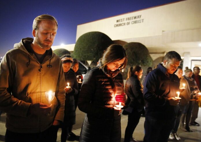 In this Monday, Dec. 30, 2019, file photo, church and community members, including Matt Pacholczyk, left, and his wife, Faith Pacholczyk, stand outside West Freeway Church of Christ for a candlelight vigil in White Settlement, Texas. (Tom Fox/The Dallas Morning News via AP, File)