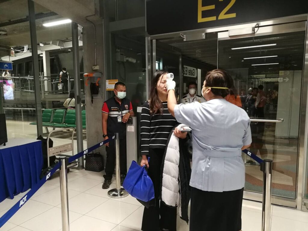 A quarantine officer uses a thermometer to check body temperature of a passenger.