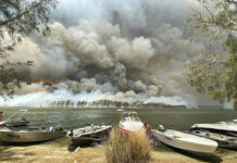 ‘Millions of Sparks’: Weather Raises Australia’s Fire Danger Boats are pulled ashore as smoke and wildfires rage behind Lake Conjola, Australia, Thursday, Jan. 2, 2020. Thousands of tourists fled Australia's wildfire-ravaged eastern coast Thursday ahead of worsening conditions as the military started to evacuate people trapped on the shore further south. Photo: Robert Oerlemans via AP