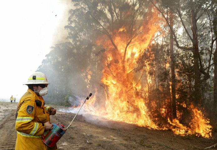 A firefighters backs away from the flames after lighting a controlled burn near Tomerong, Australia, Wednesday, Jan. 8, 2020, in an effort to contain a larger fire nearby. Photo: Rick Rycroft / AP