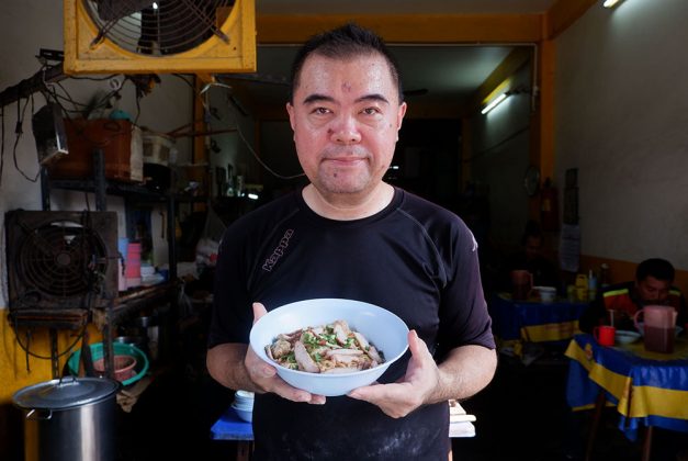 Weera Nopparatcharoeksuk, 50, holds a bowl of noodles.