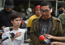 2 Motorsai Charged with Assault For Headlocking GrabBike Rider GrabBike driver Apichart Maneerat, right, and his wife speaking to reporters after he filed a complaint to the police at Phaholyothin Police Station on Jan. 24, 2020.