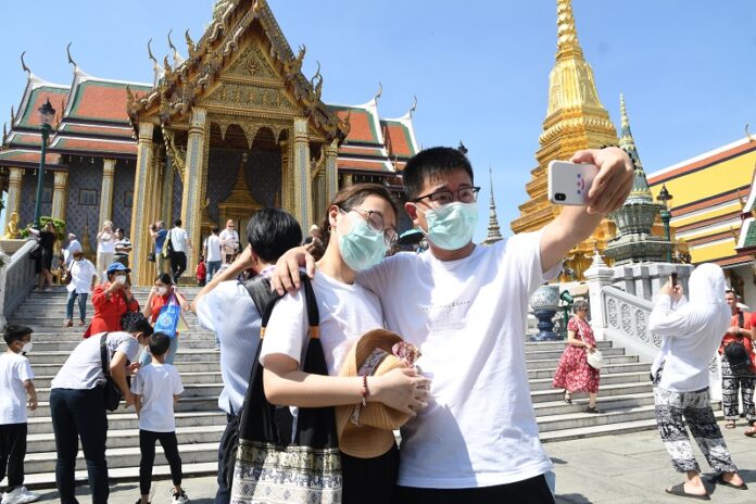 Tourists wear masks as they tour the Grand Palace complex on Jan. 26, 2020.
