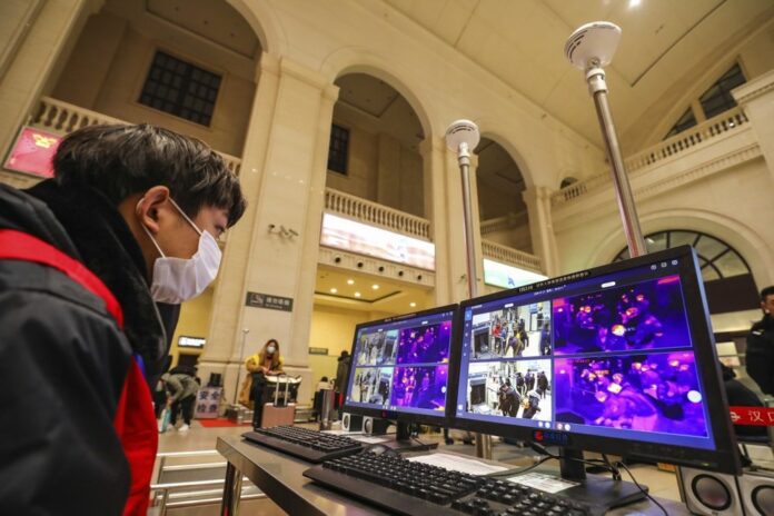 In this Tuesday, Jan. 21, 2020, photo, a worker monitors display screens for infrared thermometers as they check travelers at Hankou Railway Station in Wuhan in southern China's Hubei province. (Chinatopix via AP)