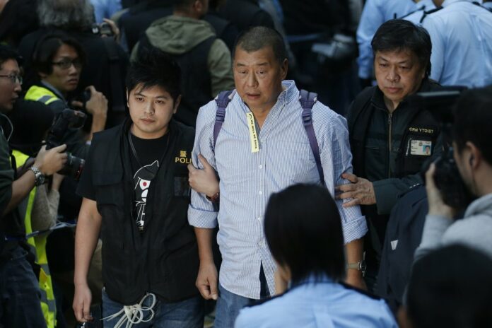 In this Dec. 11, 2014, file photo, Hong Kong media magnate Jimmy Lai, center, is taken away by police officers at the occupied area outside government headquarters in Hong Kong. (AP Photo/Kin Cheung, File)