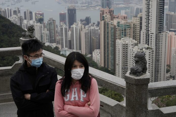 Tourists wear masks at the Peak, a popular tourist spot in Hong Kong, Sunday, Feb. 9, 2020. Health authorities are scrambling to halt the spread of a new virus that has killed hundreds in China, restricting visitors from the country and confining thousands on cruise ships for extensive screening after passengers have tested positive. (AP Photo/Kin Cheung)