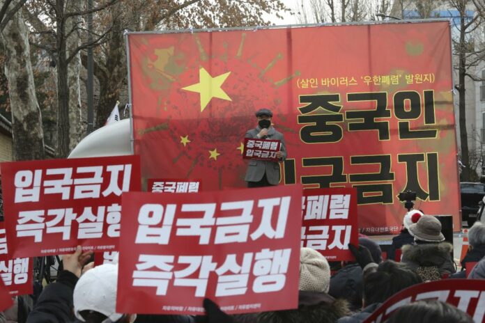 In this Wednesday, Jan. 29, 2020, photo, South Korean protesters stage a rally calling for a ban on Chinese people entering South Korea near the presidential Blue House in Seoul, South Korea. The signs read: