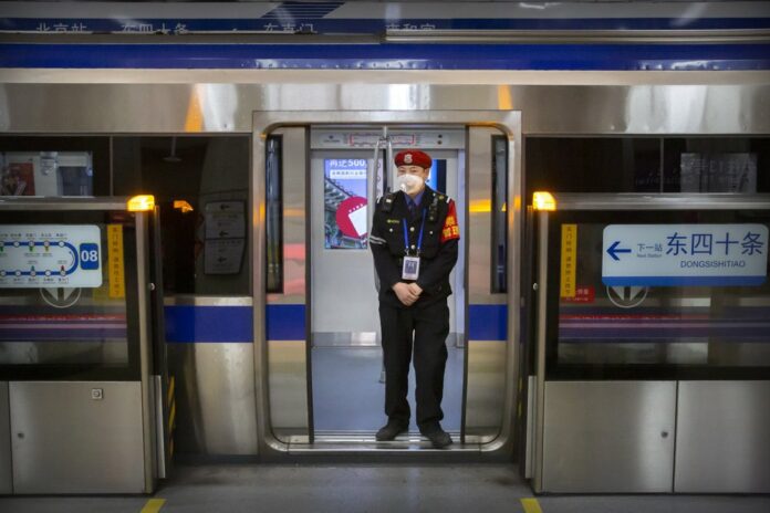 In this Feb. 3, 2020, file photo, a security officer wearing a face mask stands on a subway train in Beijing. (AP Photo/Mark Schiefelbein, File)