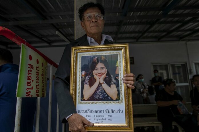Khunpol Khanpakwan holds a portrait of his daughter Apiksanapa Khanpakwan outside a hospital morgue in Nakhon Ratchasima, Thailand, Monday, Feb. 10, 2020. (AP Photo/Gemunu Amarasinghe)