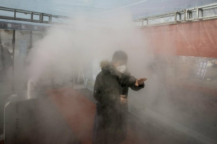 A man walks through a disinfectant spray in order to return home at a residential complex in northern China's Tianjin Municipality Tuesday, Feb. 11, 2020. (Chinatopix Via AP) CHINA OUT