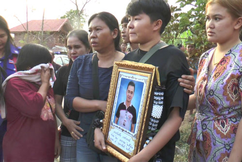 Relatives of Wanchai Vechawan holding his funeral photo on Feb. 11 in Buriram province.