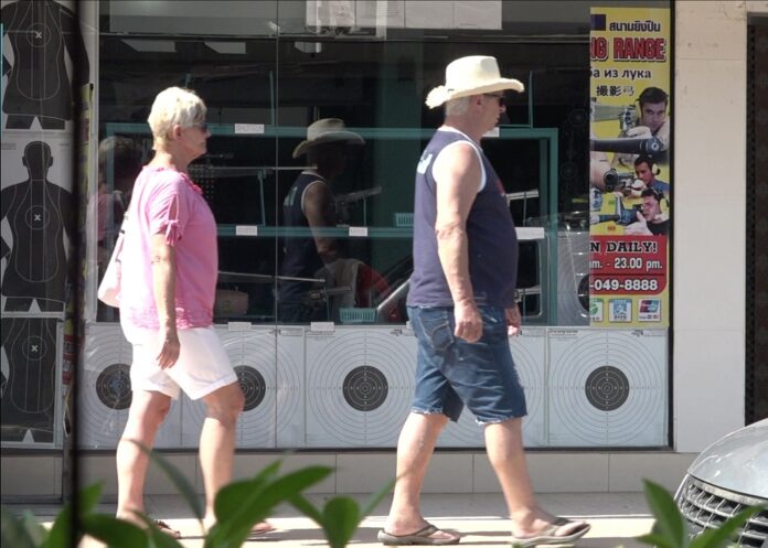 Tourists walk past a gun range on Koh Samui on Jan. 30, 2020.