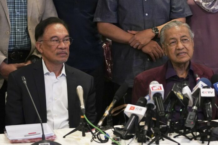 In this Feb. 22, 2020, photo, Malaysian Prime Minister Mahathir Mohamad, right, talks to media next to his successor Anwar Ibrahim in Putrajaya, Malaysia. (AP Photo/Vincent Thian)