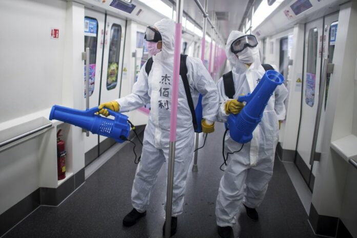 In this March 23, 2020 photo released by Xinhua News Agency, workers disinfect a subway train in preparation for the restoration of public transport in Wuhan, in central China's Hubei province. (Xiao Yijiu/Xinhua via AP)