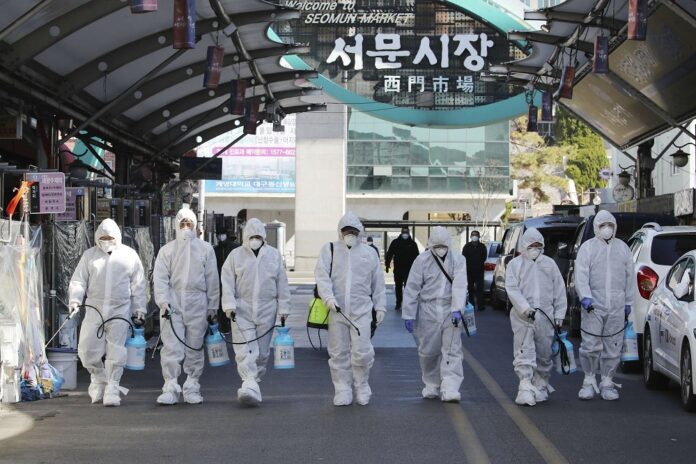Workers wearing protective gears spray disinfectant as a precaution against the COVID-19 at a local market in Daegu, South Korea, Sunday, Feb. 23, 2020. (Im Hwa-young/Yonhap via AP)