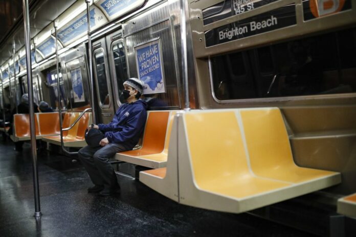 A commuter wears a face mask while riding the a nearly empty subway car into Brooklyn, Thursday, March 12, 2020, in New York. (AP Photo/John Minchillo)