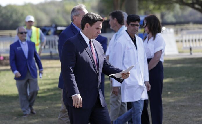In this March 23, 20202 file photo, Florida Gov. Ron DeSantis, center front, arrives at a mobile testing site for a press conference Monday, March 23, 2020, in The Villages, Fla. (AP Photo/John Raoux, File)