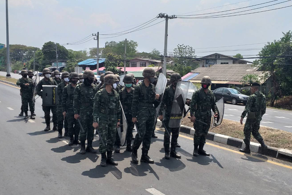 Soldiers in riot gear stand guard in front of the prison.