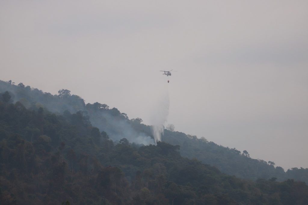 A navy helicopter drops water on the wildfire in Trat province.