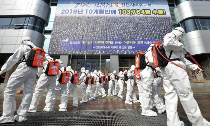 Army soldiers wearing protective suits spray disinfectant to prevent the spread of the coronavirus in front of a branch of the Shincheonji Church of Jesus in Daegu, South Korea, Sunday, March 1, 2020. (Lee Moo-ryul/Newsis via AP)