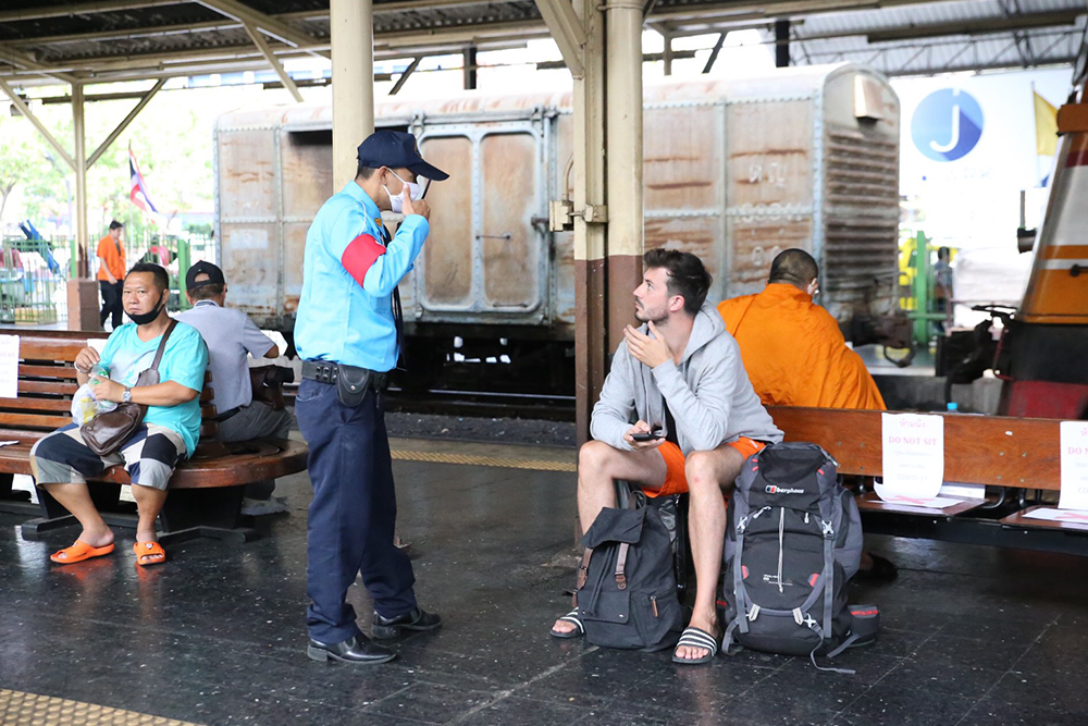 A security guard tells a foreigner to wear a mask at Hua Lamphong Railway Station.