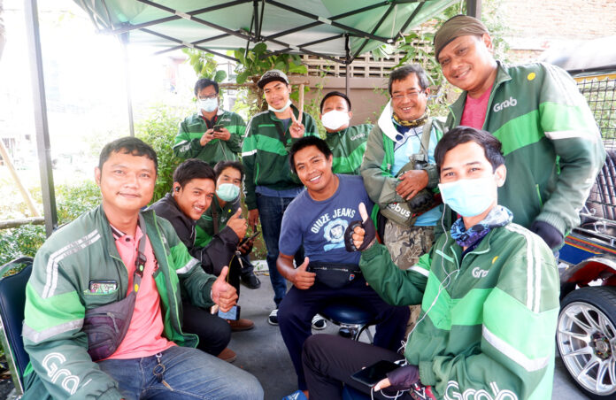 The group of Grab drivers in front of The Marketplace Nanglinchee. Thanakorn Krantakul is in glasses, Sompong Jaidee is in red, at right, and Teerapong Supasai seated furthest away and wearing a mask.