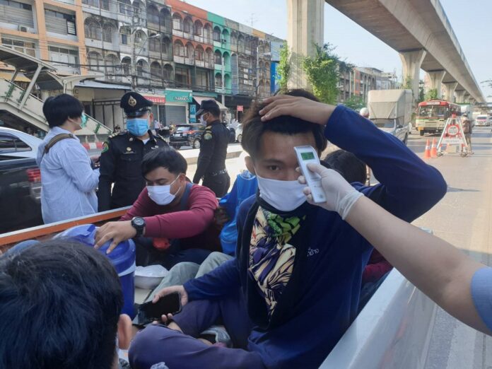 Commuters get temperature checked at a police checkpoint in Bangkok on March 26, 2020.