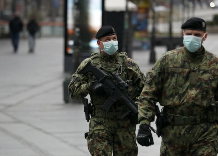 In this March 26, 2020, photo, Serbian army soldiers patrol in Belgrade's main pedestrian street, in Serbia. (AP Photo/Darko Vojinovic)