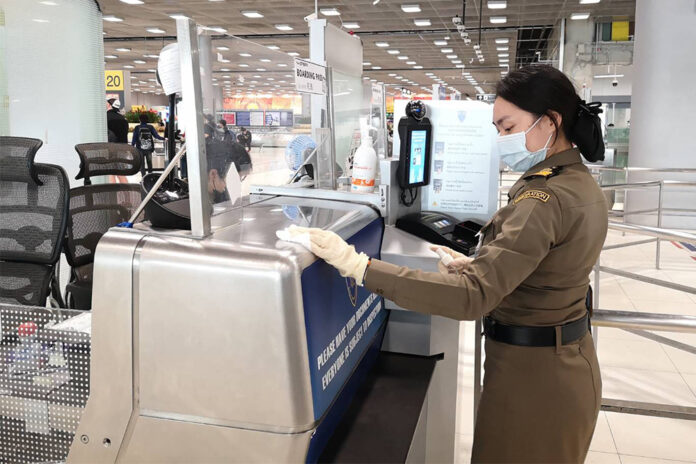 An immigration officer disinfects an immigration desk at Suvarnabhumi Airport on March 11, 2020.