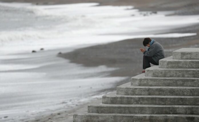 A woman prays at a beach in Iwaki, Fukushima Prefecture, on March 11, 2019, the eighth anniversary of the 2011 earthquake-tsunami disaster in northeastern Japan.