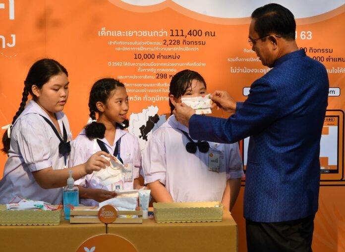 PM Prayut Chan-o-cha puts a mask on a school student during an exhibition at Government House on March 3, 2020.