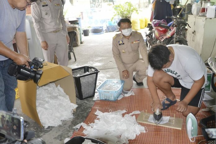 A worker at a shop in Saraburi shows police how he and other employees allegedly wash and iron used face masks for reselling on March 3, 2020.