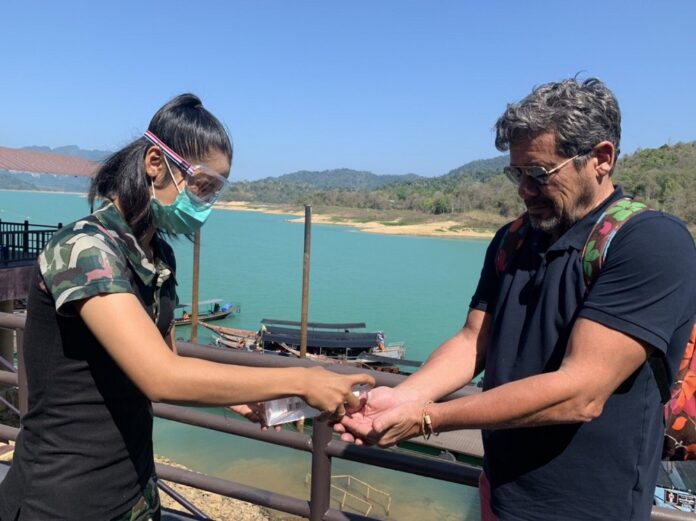 Workers dispense a hand sanitizer to foreign tourists in Surat Thani province on March 15, 2020.