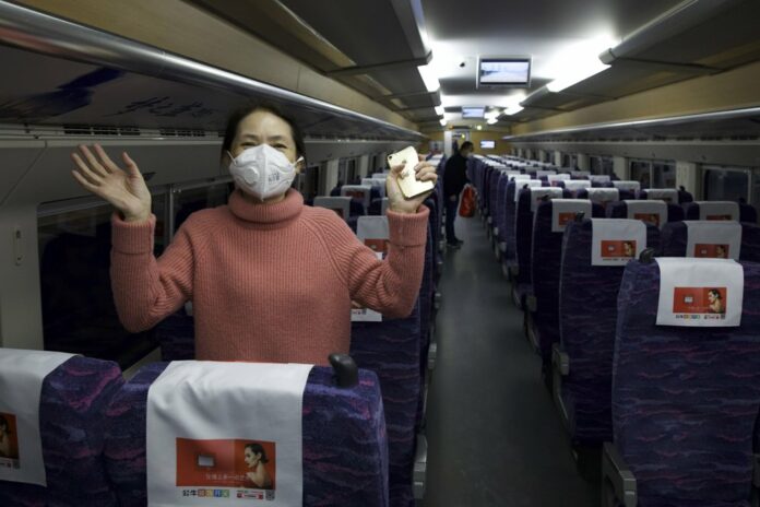 A passenger wearing a face mask to protect against the spread of new coronavirus talks about how happy she is to leave her 76-day stay in lockdown in Wuhan as she boards the first high-speed train to leave Hankou train station after the resumption of train services in Wuhan in central China's Hubei Province, Wednesday, April 8, 2020. (AP Photo/Ng Han Guan)