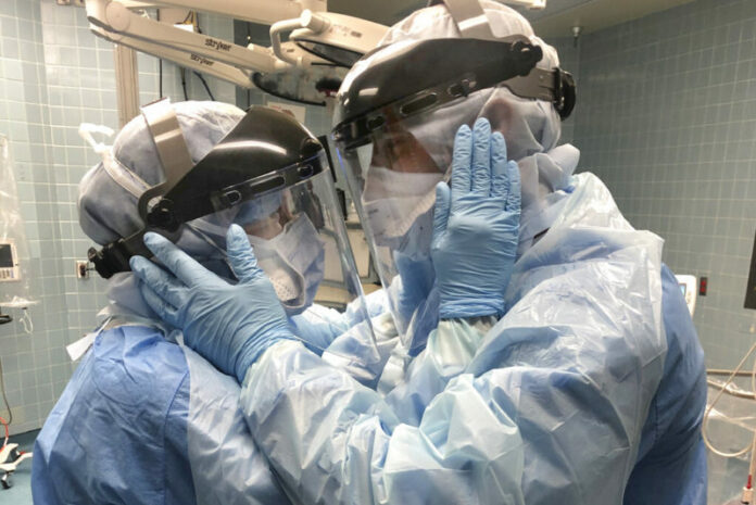 In this March 30, 2020 photo provided by Chief Nurse Anesthetist Nicole Hubbard, nurses Mindy Brock and Ben Cayer, wearing protective equipment, hold each other and look into each other's eyes, in Tampa General Hospital in Tampa, Fla. Photo: Nicole Hubbard / AP