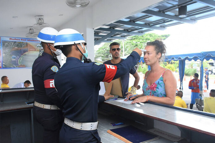 A foreign tourist gets her temperature checked by military police officers at Ao Manao in Prachuap Khiri Khan province on March 19, 2020.