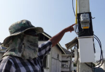 Electricity Bill Discounts Approved to Aid Stay-At-Home Policies A woman points to an electric meter in Chonburi province on April 21, 2020.