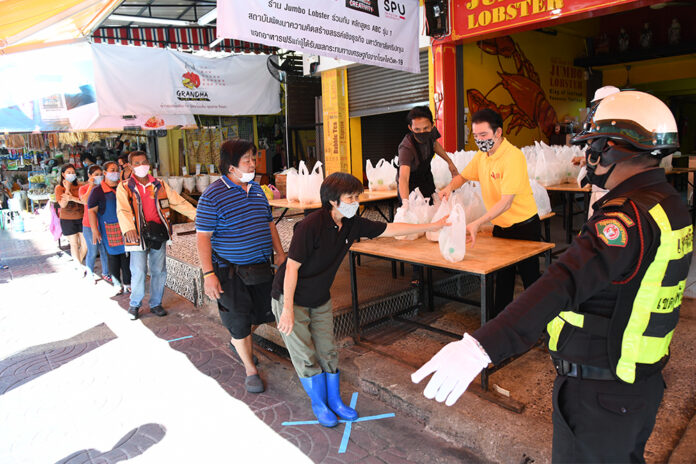 People observe social distancing measures by keeping distance from each other at a food handout event in Bangkok on April 21, 2020.