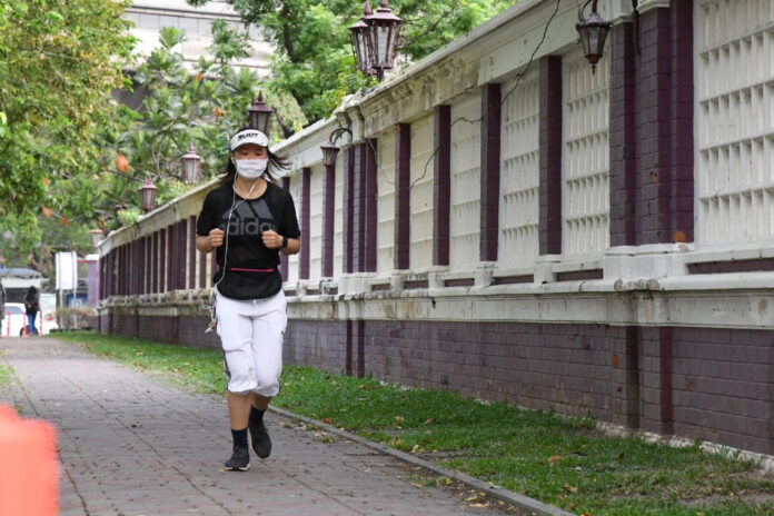 A woman jogs outside Lumpini Park.