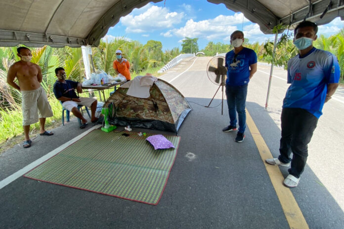 Thai workers returning from Malaysia stand by a tent at a quarantine facility in Trang’s Kantang district on April 2, 2020.