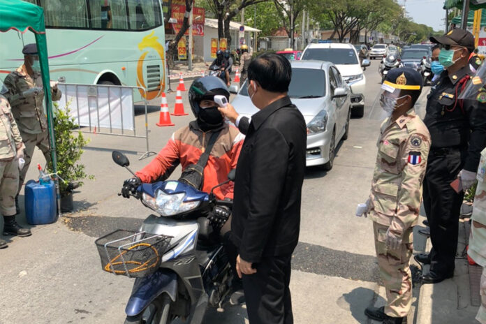 Prime Minister Prayut Chan-o-cha checks the temperature of a motorcyclist during his visit to a checkpoint on April 12, 2020.