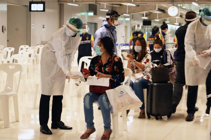 A health official in protective clothing talks to a woman at a health quarantine checkpoint at Suvarnabhumi Airport on April 16, 2020.