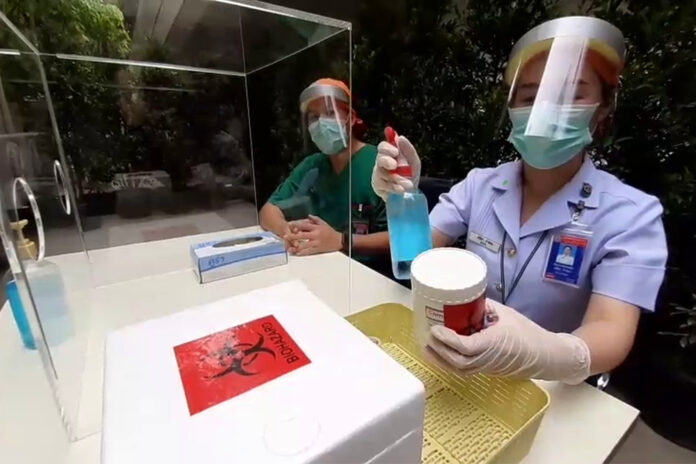 A nurse at Bhumibol Adulyadej Hospital disinfects a biohazard container on April 28, 2020.