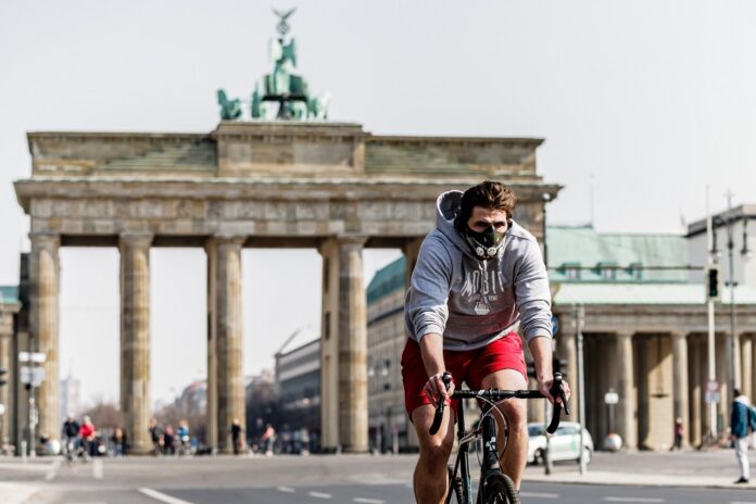 A bicyclist wearing a face mask is seen near the Brandenburger Gate in Berlin, capital of Germany, March 28, 2020. (Photo by Binh Truong/Xinhua)