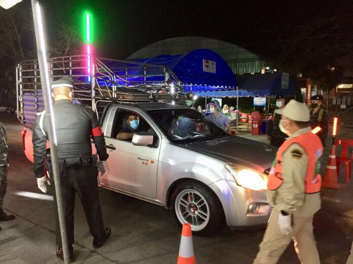 Security officers question a driver during curfew hours in Suphanburi province on April 6, 2020.